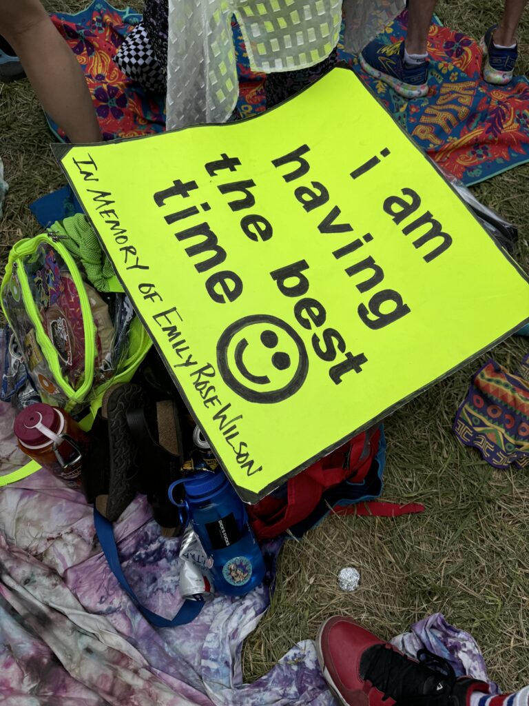 Neon sign on the ground reading “I am having the best time,” in memory of Emily Rose Wilson.