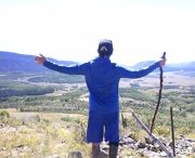 Jeffrey Emblidge standing on a mountain overlook with his arms stretched wide, facing the landscape.