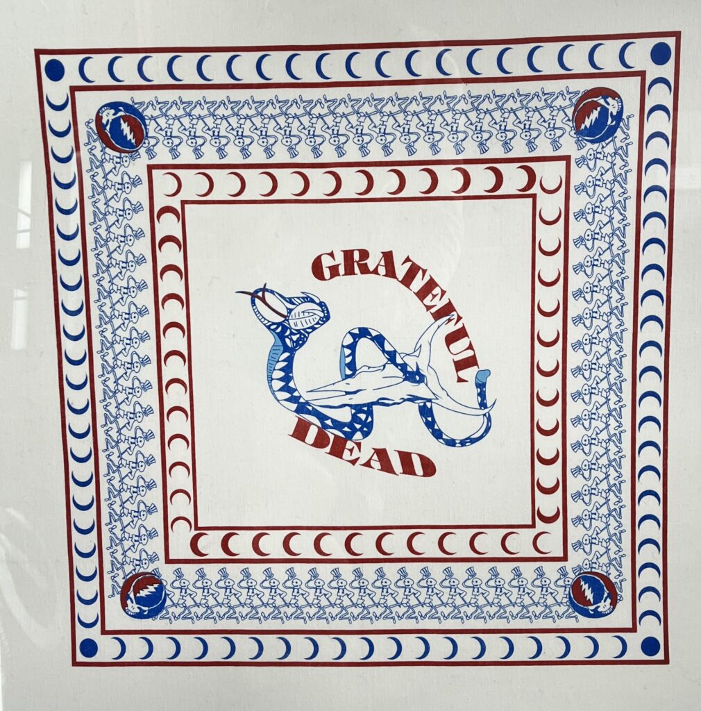 White Grateful Dead bandana with red and blue print, dancing skeleton borders, stealie corners, and a central “Grateful Dead” design.