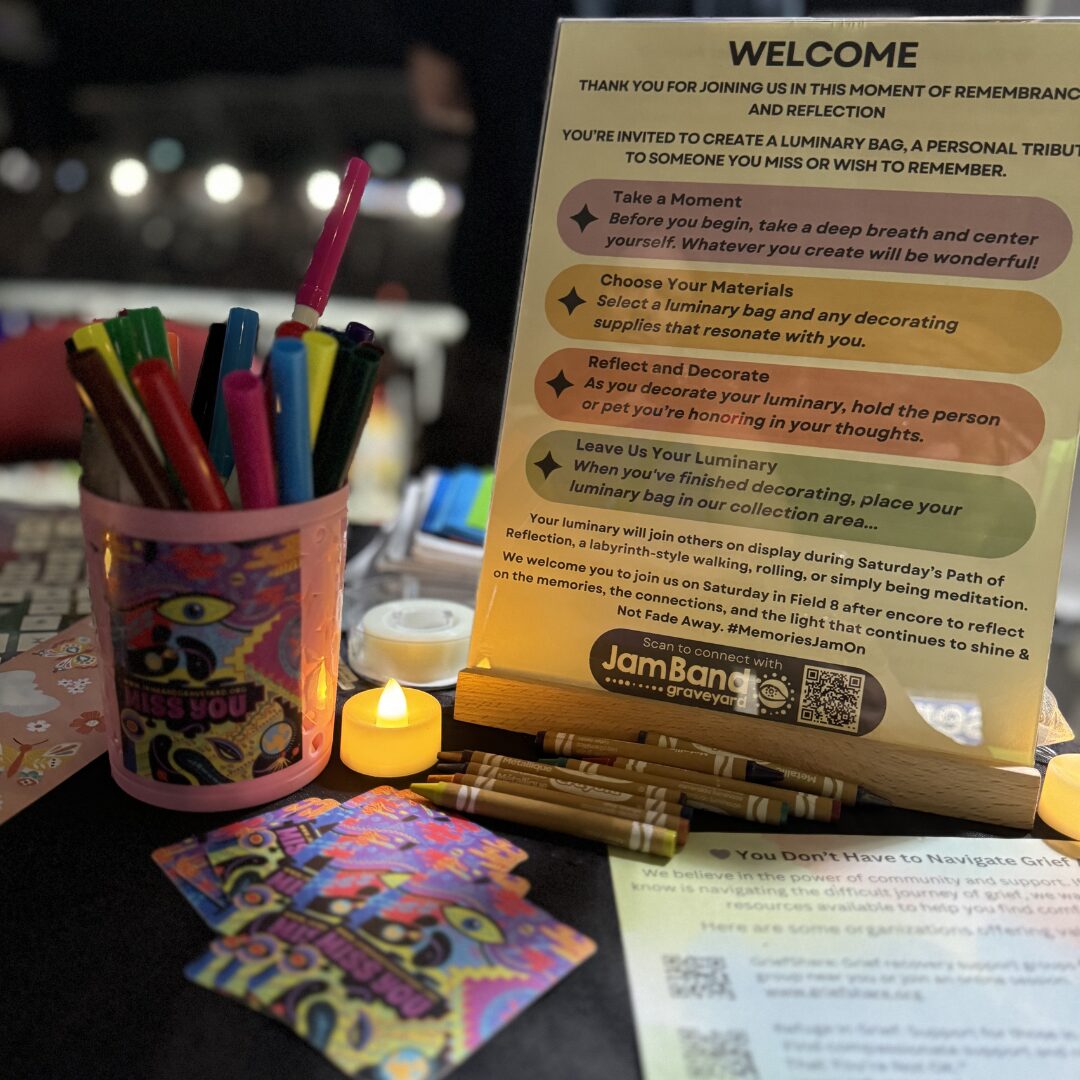 Jam Band Graveyard luminary decorating table with candles, markers, and remembrance materials at a community event (Phish Dick's 2024)